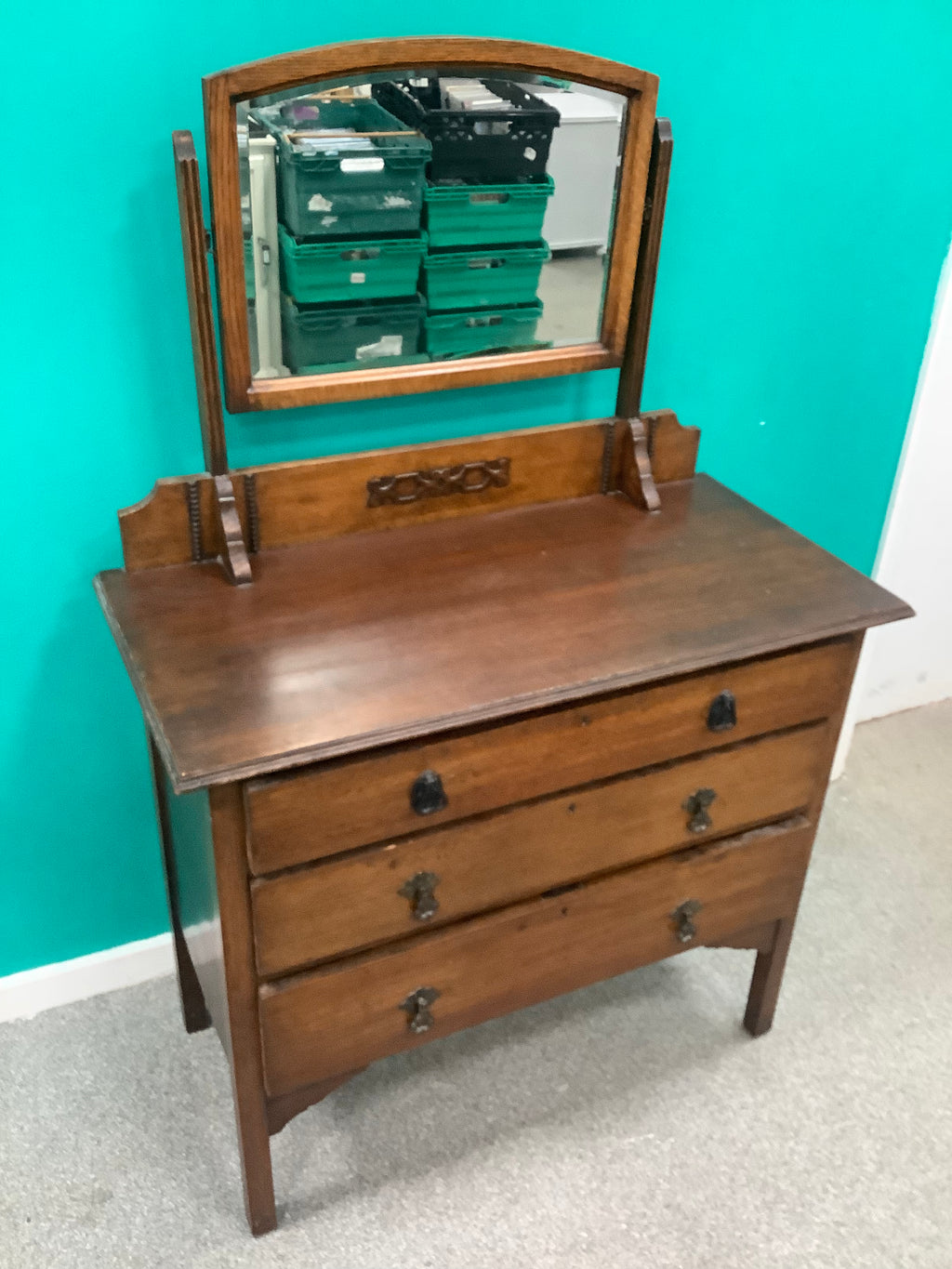 An antique Edwardian Arts & and Crafts dark oak dressing chest featuring a swing vanity mirror, decorative pierced metal drop handles, and a three-drawer configuration. 170826009
