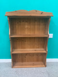 solid pine wall-hanging shelving unit or dresser top rack featuring a scalloped/arched crest rail and three fixed open shelves with a tongue-and-groove panel 190826001