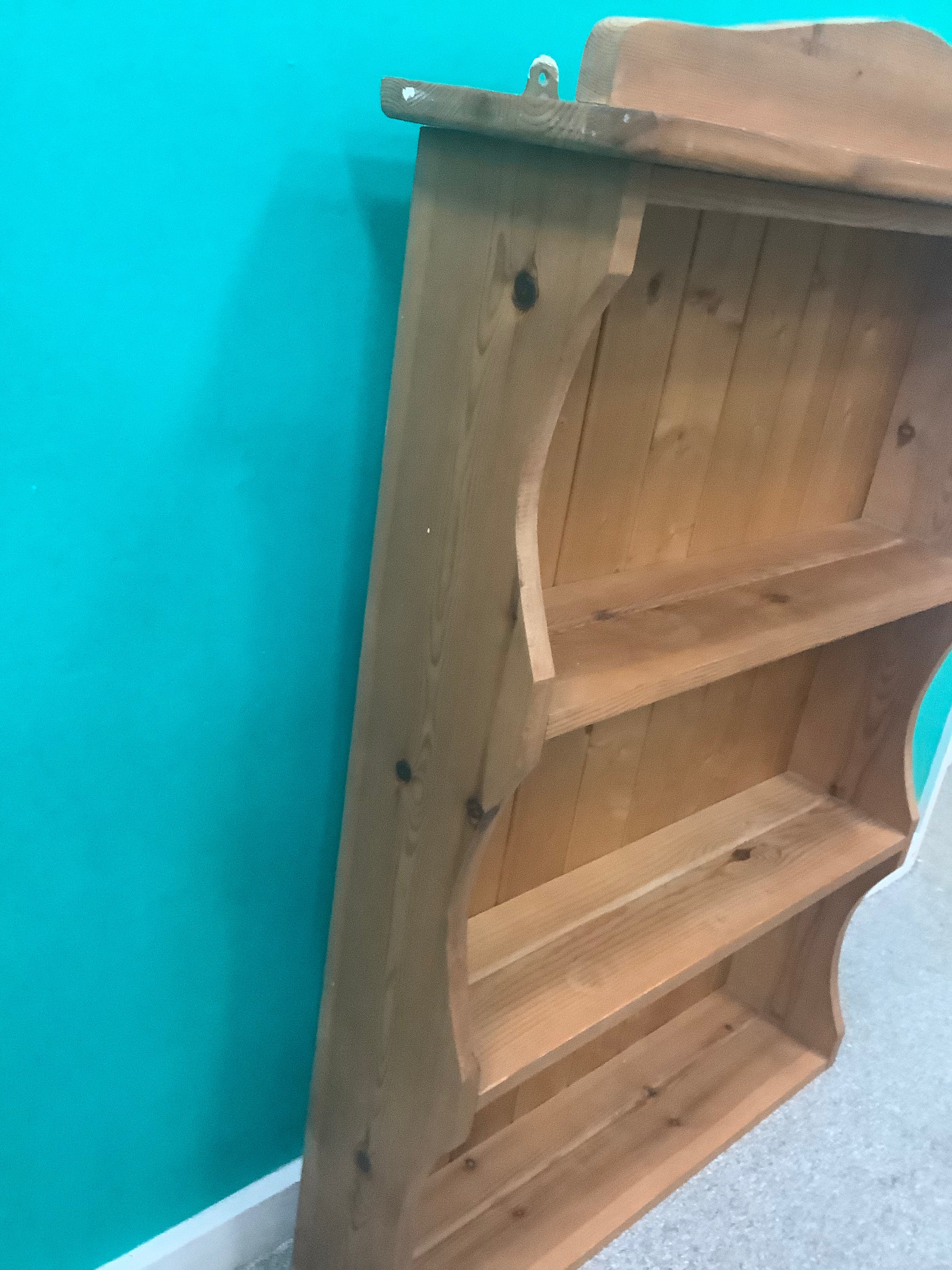 solid pine wall-hanging shelving unit or dresser top rack featuring a scalloped/arched crest rail and three fixed open shelves with a tongue-and-groove panel 190826001