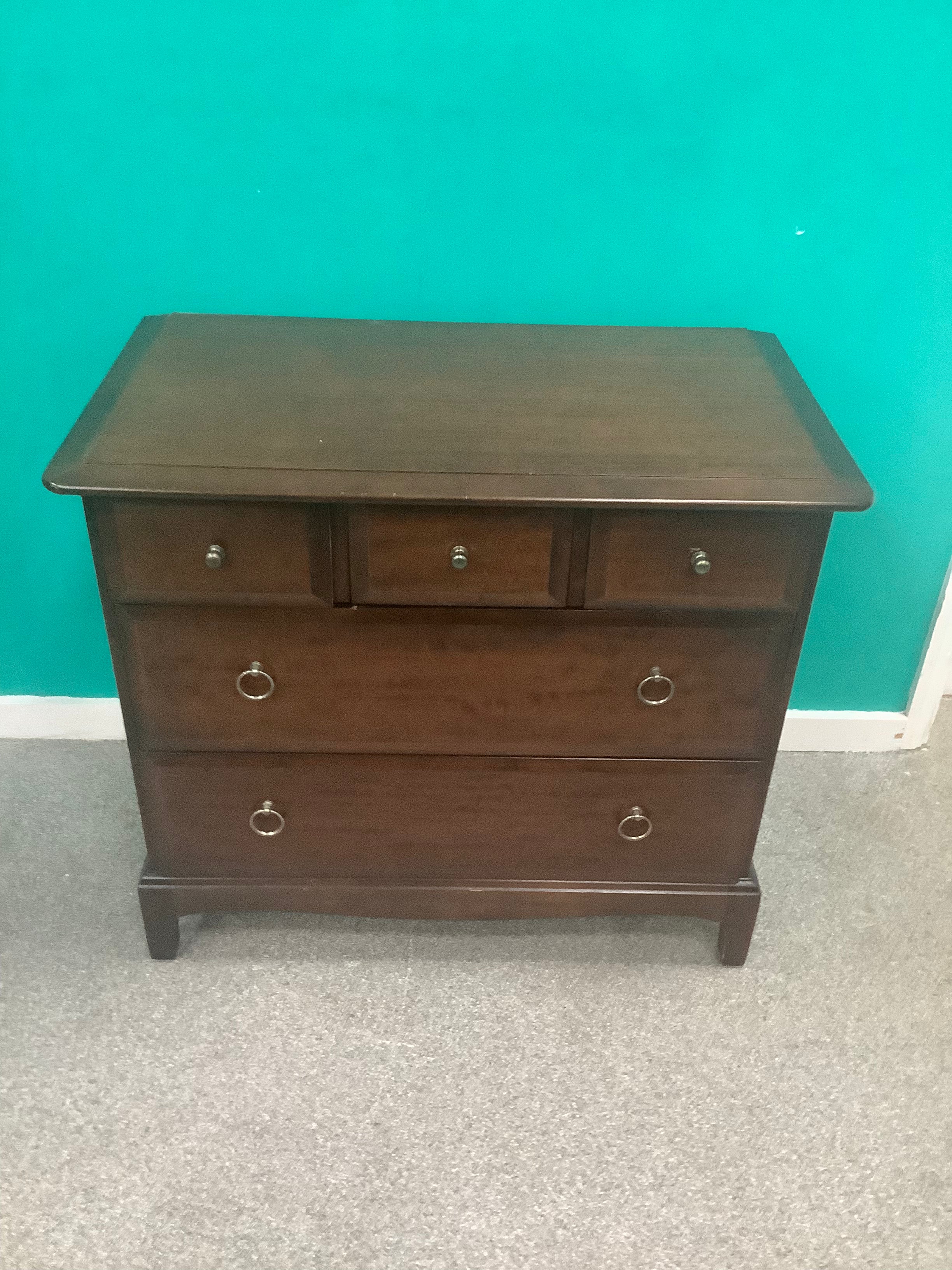 Stag Minstrel 3-over-2 chest of drawers, designed by John & Sylvia Reid in the mid-20th century and crafted from mahogany or cherry veneers with distinctive brass-toned ring pull handles. 190826003