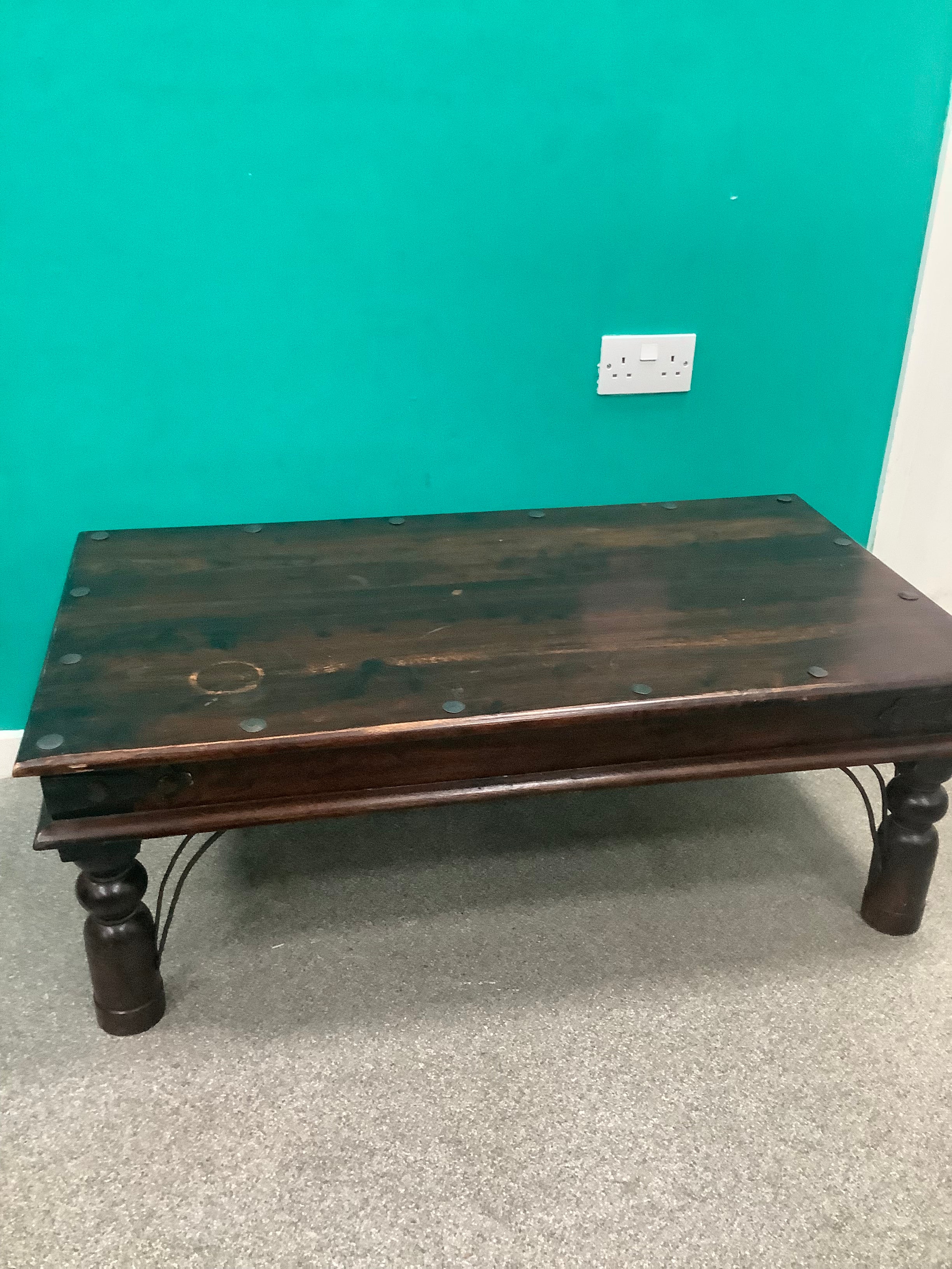 rustic dark solid wood coffee table features a rich stained top accented with decorative metal studs along the edge and turned bulbous legs. 210826002