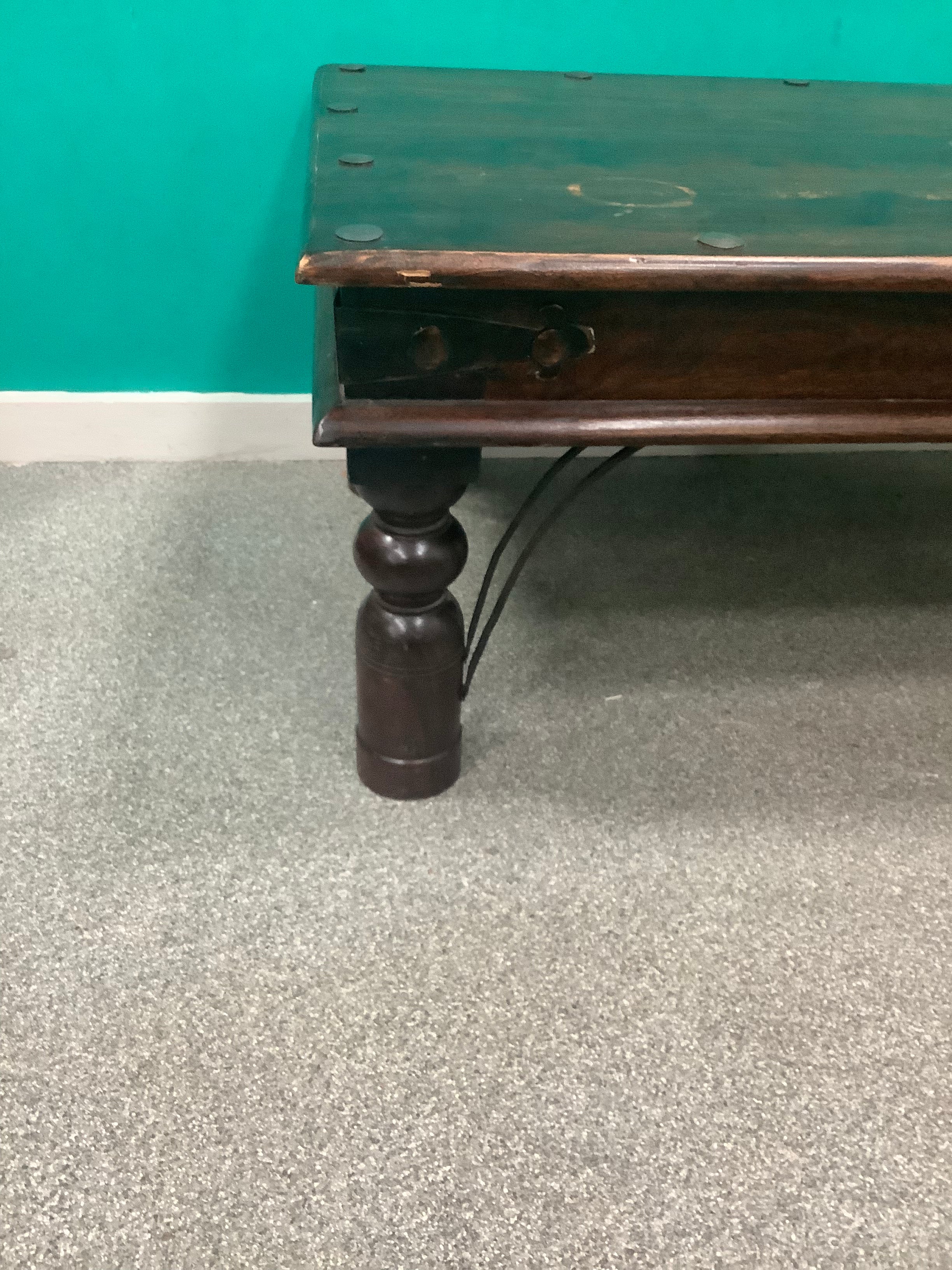 rustic dark solid wood coffee table features a rich stained top accented with decorative metal studs along the edge and turned bulbous legs. 210826002