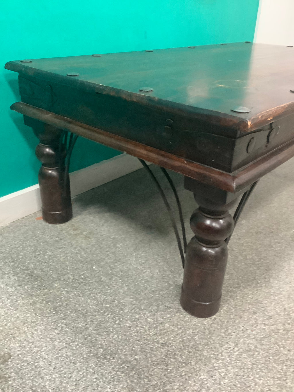 rustic dark solid wood coffee table features a rich stained top accented with decorative metal studs along the edge and turned bulbous legs. 210826002