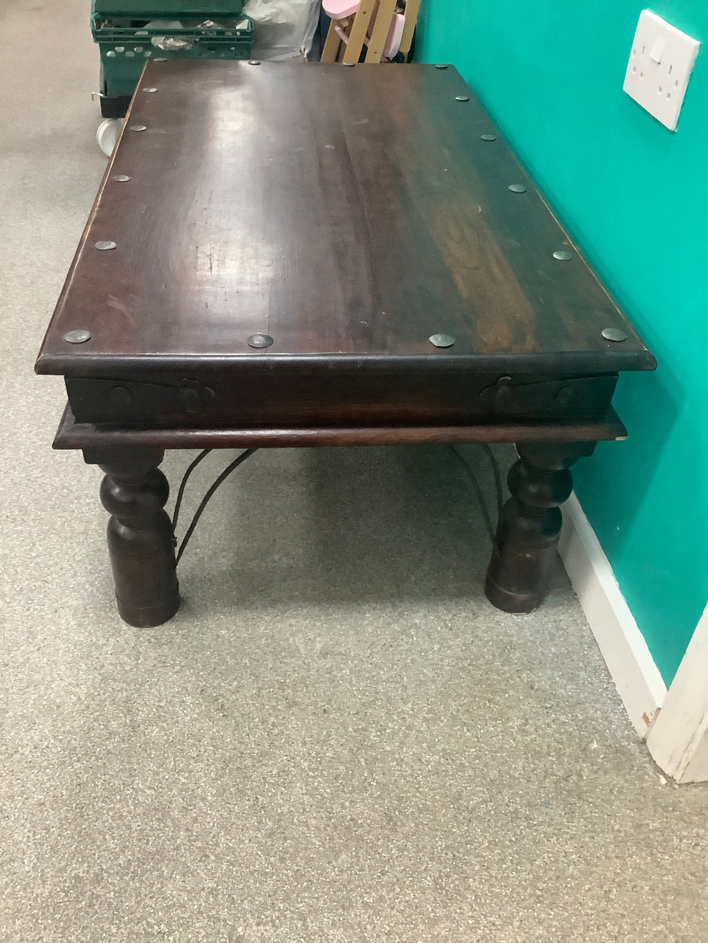 rustic dark solid wood coffee table features a rich stained top accented with decorative metal studs along the edge and turned bulbous legs. 210826002