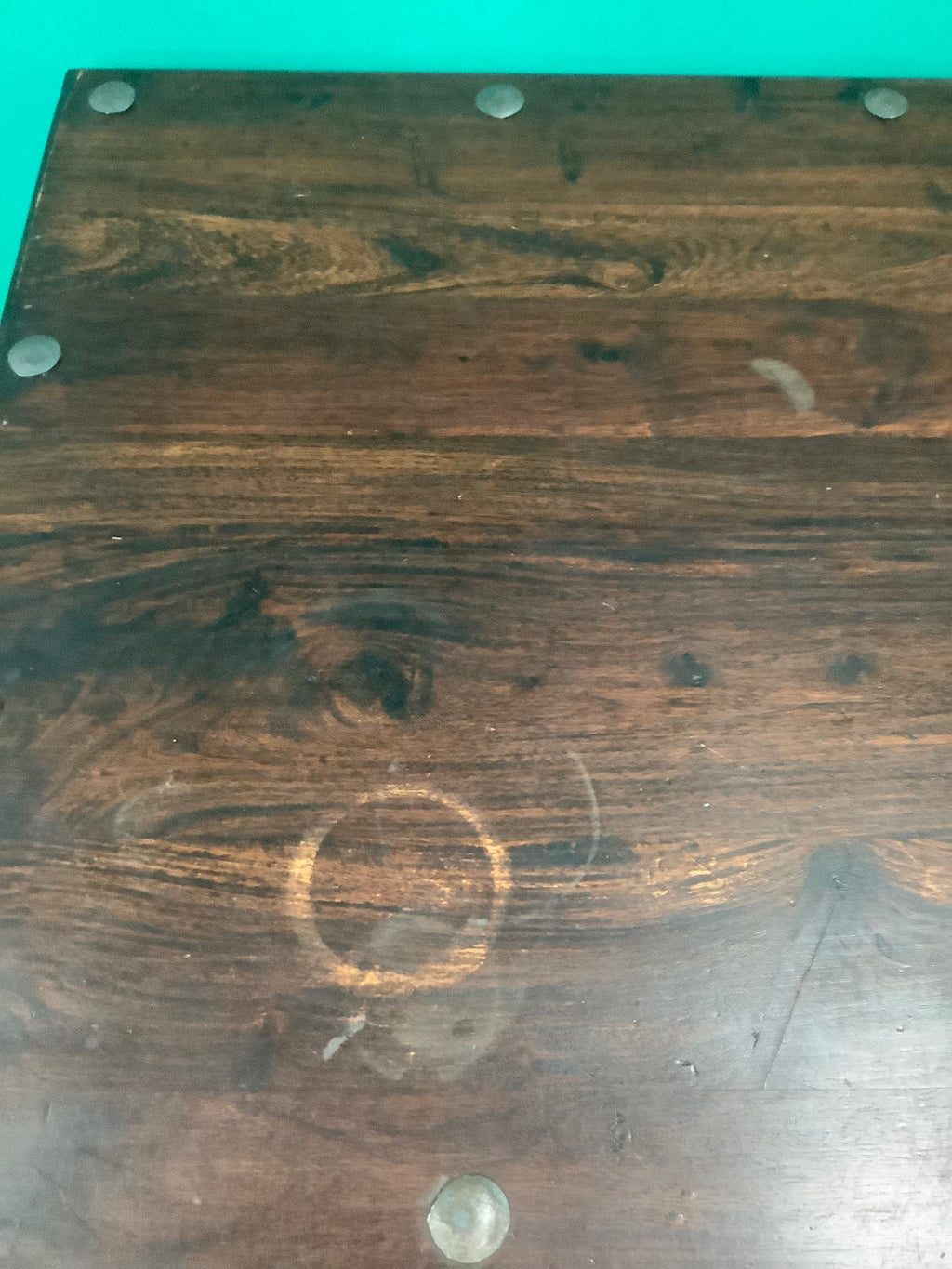 rustic dark solid wood coffee table features a rich stained top accented with decorative metal studs along the edge and turned bulbous legs. 210826002