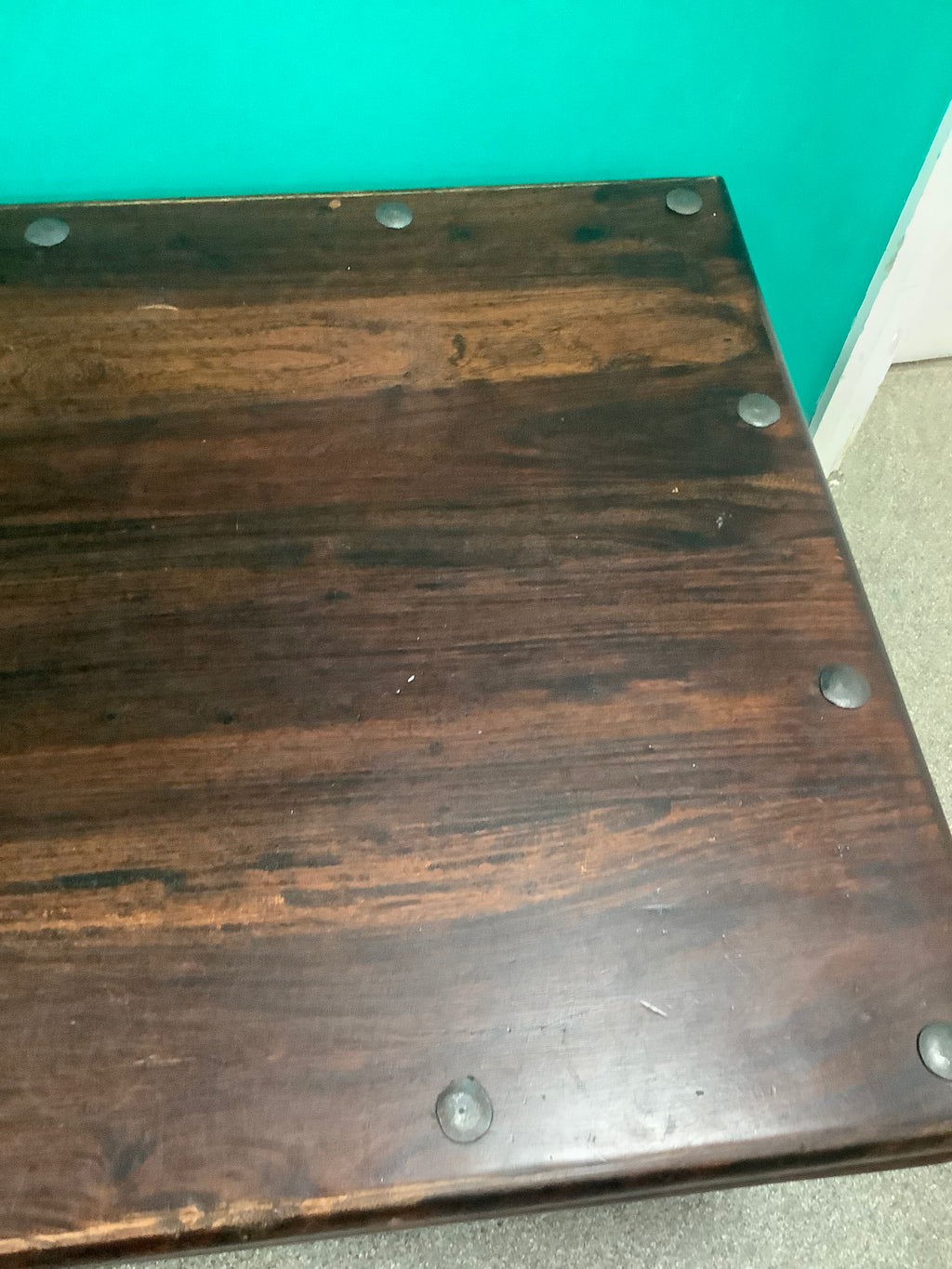 rustic dark solid wood coffee table features a rich stained top accented with decorative metal studs along the edge and turned bulbous legs. 210826002