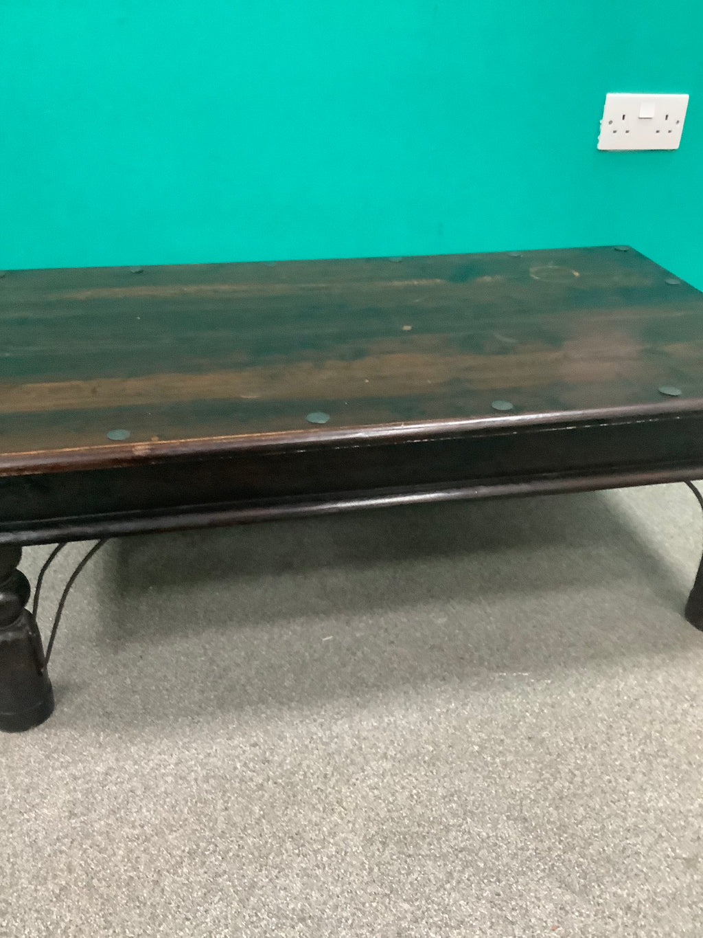 rustic dark solid wood coffee table features a rich stained top accented with decorative metal studs along the edge and turned bulbous legs. 210826002