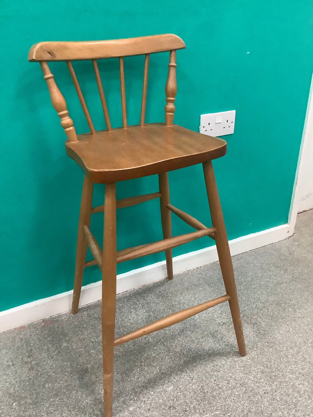 Windsor-style wooden bar stool features a spindle-back design with turned leg supports and multiple footrest stretchers for stability.210826004