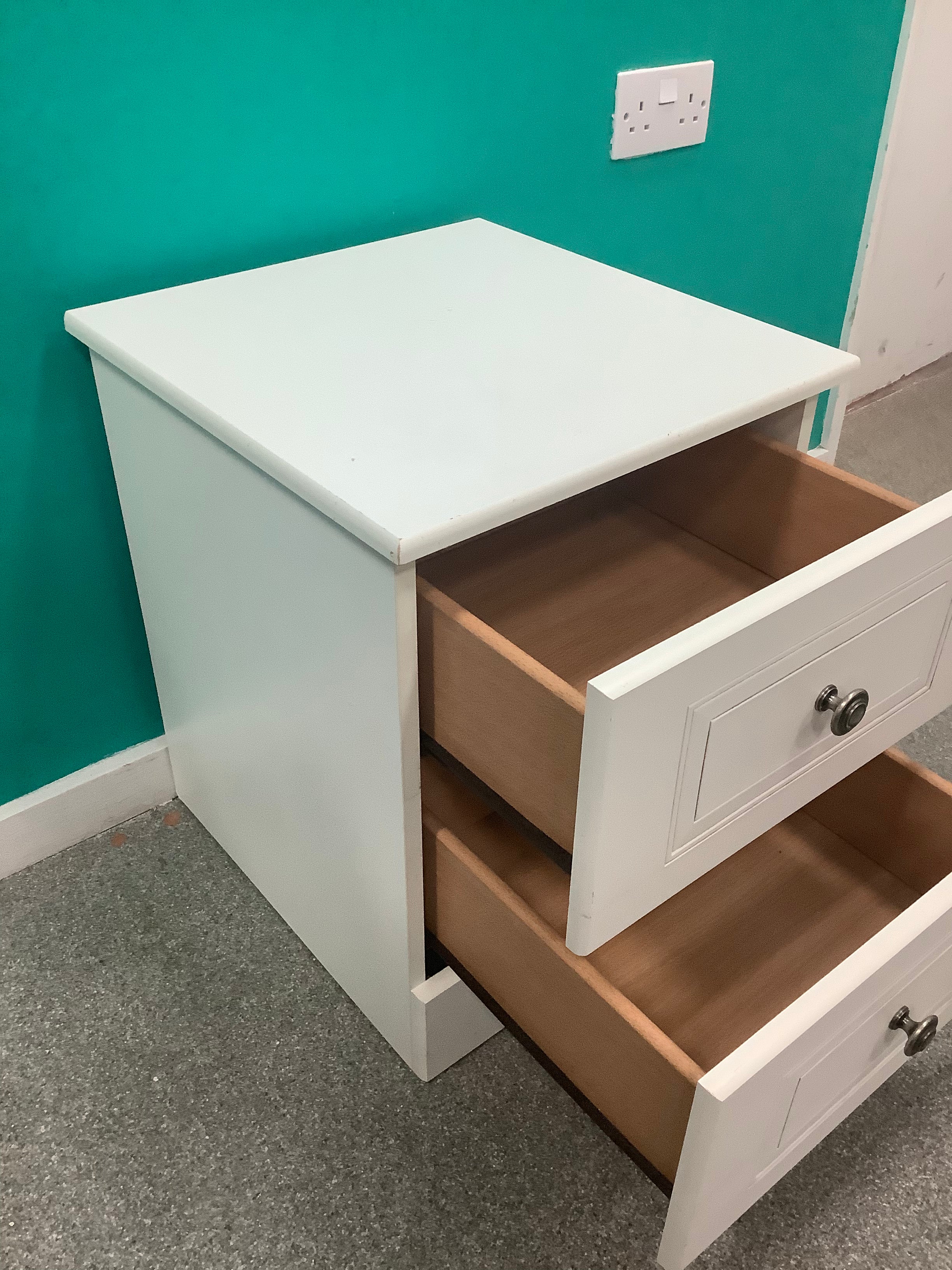 white 2-drawer bedside locker shown is a traditional freestanding nightstand featuring recessed drawer panels and round metal knobs. 210826006