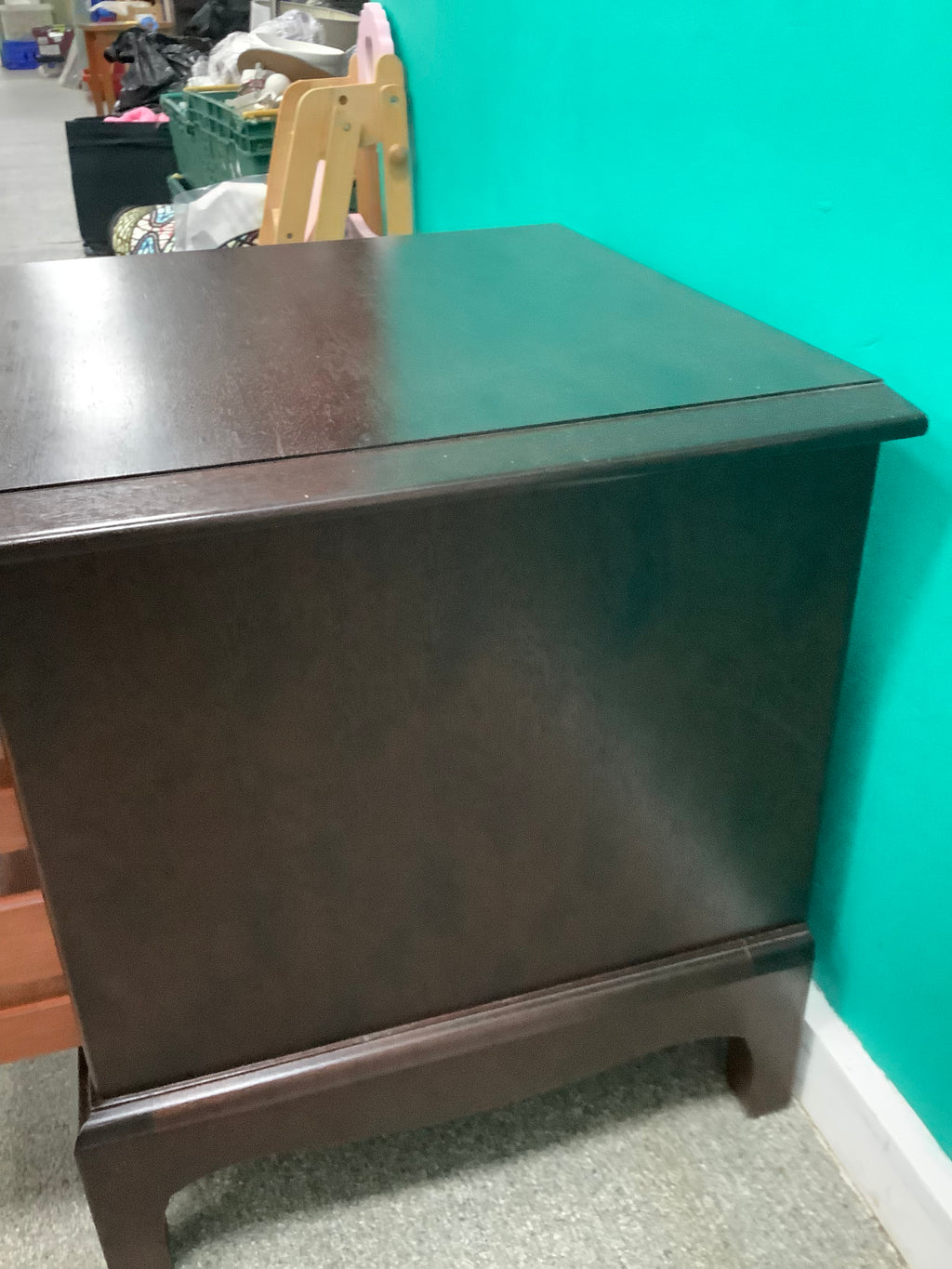 Stag Minstrel mahogany bedside cabinet featuring a pull-out sliding shelf above two drawers with distinctive brass-toned ring pulls. 240826001