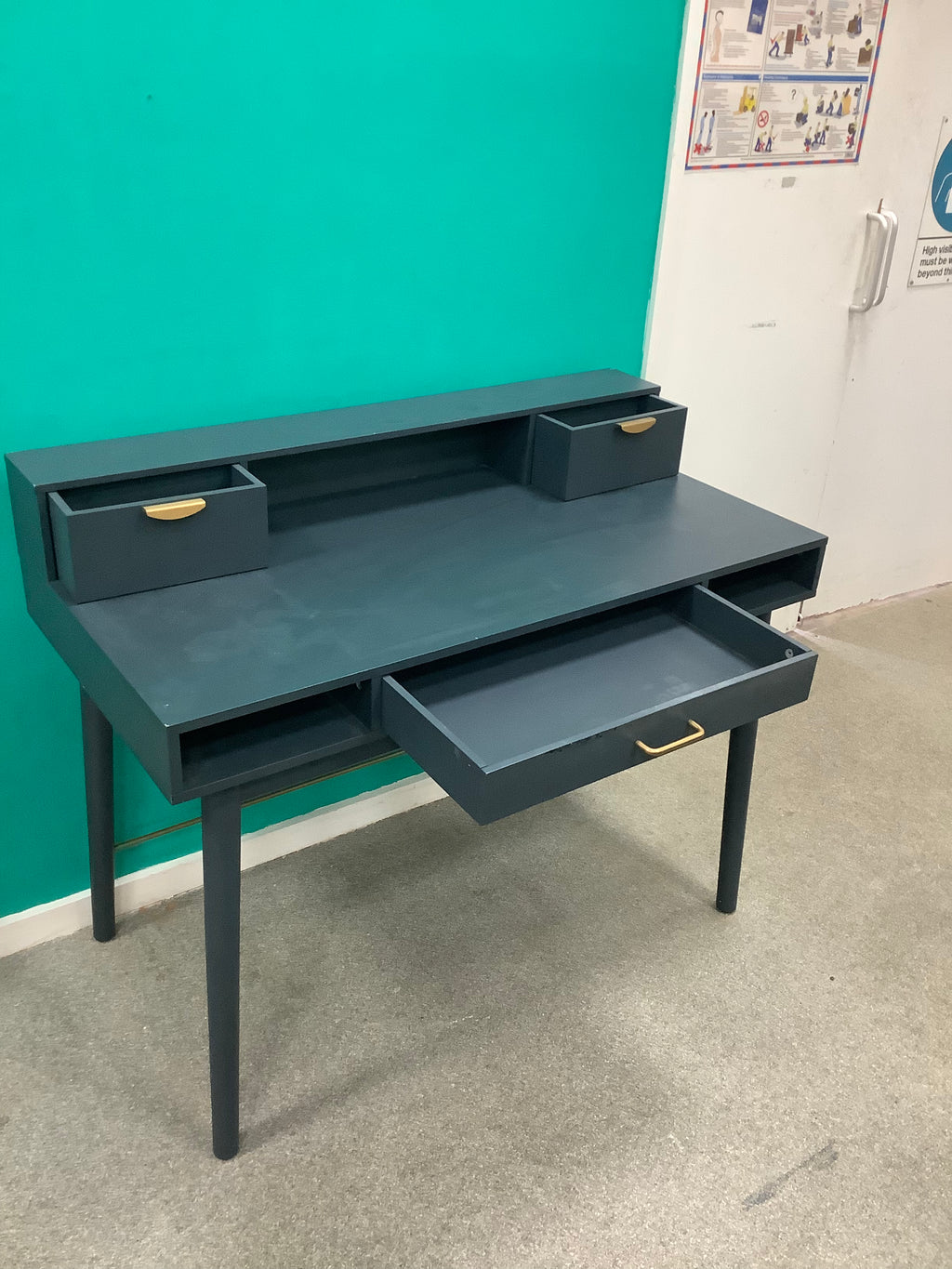 This is the dark blue or charcoal vintage-style "Penelope" 3-drawer desk by Maisons du Monde, featuring distinct brass-finish half-moon handle pulls and an elevated upper tier with integrated small compartments. 240826004